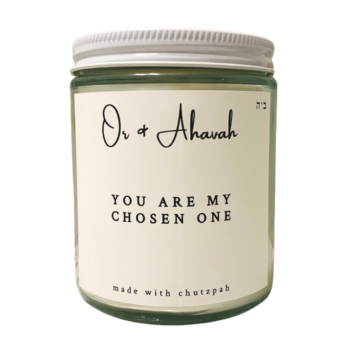 Clear glass candle with a white metal lid. Brand name is Or & Ahavah. Candle name is You Are My Chosen One. At the bottom, it says made with chutzpah. Scent notes are sea salt, cardamom seed, amber, and clove.