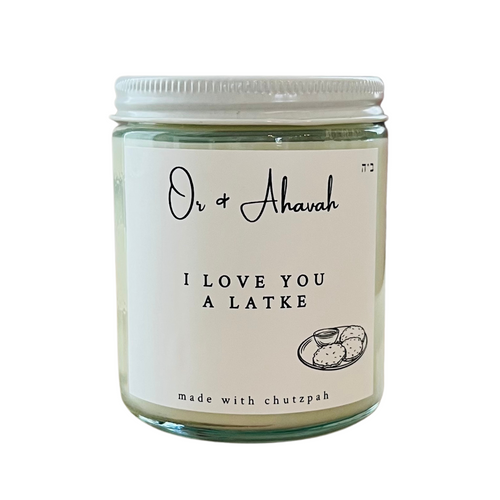 Clear glass candle with a white metal lid. Brand name is Or & Ahavah. Candle says 